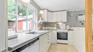 A modern kitchen with white cabinets, a Siemens dishwasher, a built-in oven, and a window with a view of greenery. - Cozy home in Ebeltoft with WiFi (Ebeltoft)