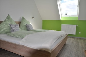 Ein Schlafzimmer mit Bett, Kissen, Heizkörper und Dachfenster.