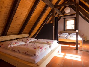 Ein Schlafzimmer mit zwei Betten, Holzbalken, einem Fenster und einer Hängelampe.