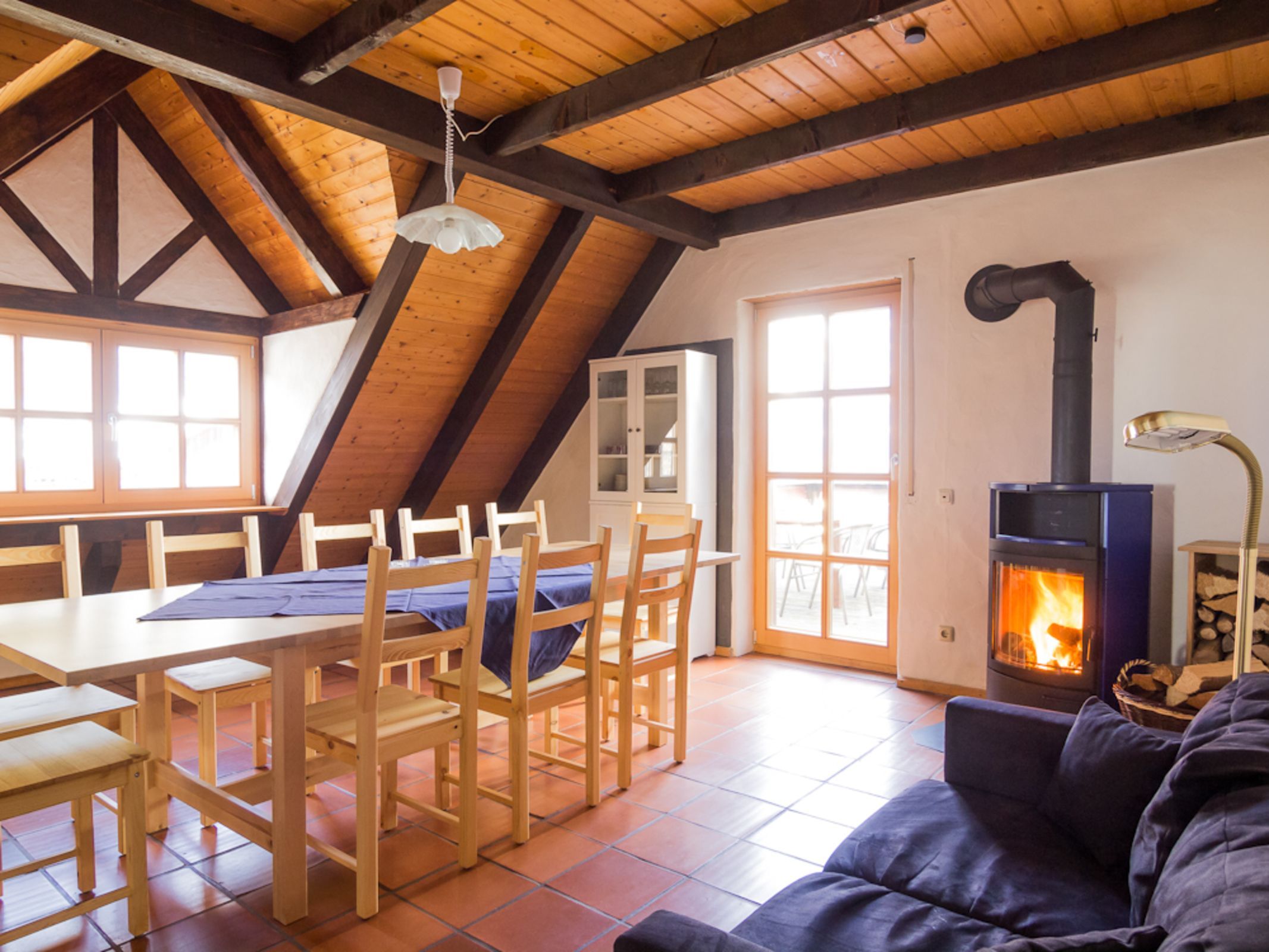 Una stanza accogliente con soffitto in legno, un tavolo da pranzo con sedie, un divano, un camino e una finestra.