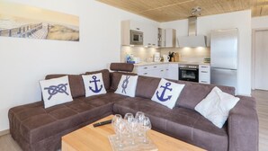 Un'accogliente zona giorno con un divano marrone, un tavolino in legno e una cucina sullo sfondo.