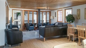 Ein großzügiger Wohnbereich mit Holzboden, einer Couch, Sesseln und einem Esstisch.