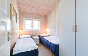 Une petite chambre agréable, dotée de deux lits simples, d’une fenêtre et d’un plafond en bois.