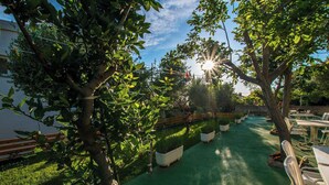 Un patio jardín con mobiliario exterior, plantas en macetas y una valla de madera.