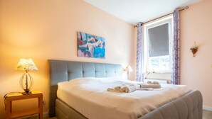A neatly made bed with a grey headboard, a bedside table with a lamp, and a painting on the wall. - Strandstr. 31 apt. MA-03. - Strandstrasse 31 apt. 03 (Kühlungsborn)