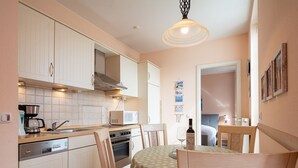 A compact kitchen with white cabinets, a microwave, a coffee maker, and a dining table with chairs. - Strandstr. 31 apt. MA-03. - Strandstrasse 31 apt. 03 (Kühlungsborn)