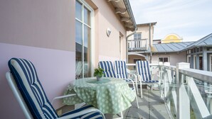 A balcony with striped chairs and a table, overlooking a building with a yellow roof. - Strandstr. 31 apt. MA-03. - Strandstrasse 31 apt. 03 (Kühlungsborn)