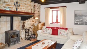 A cozy living room with a stone fireplace, a sofa set, a wooden coffee table, and a window with curtains. - Beautiful home in Montaudin with WiFi (Montaudin)