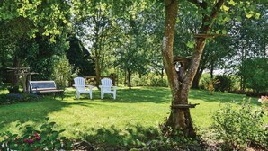 A garden with a bench, two Adirondack chairs, and a tree. - Beautiful home in Montaudin with WiFi (Montaudin)
