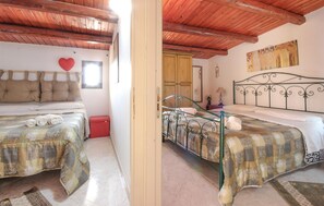 A room with two beds, a wooden ceiling, a red heart decoration, and a painting on the wall. - Awesome home in Menfi AG (Menfi AG)