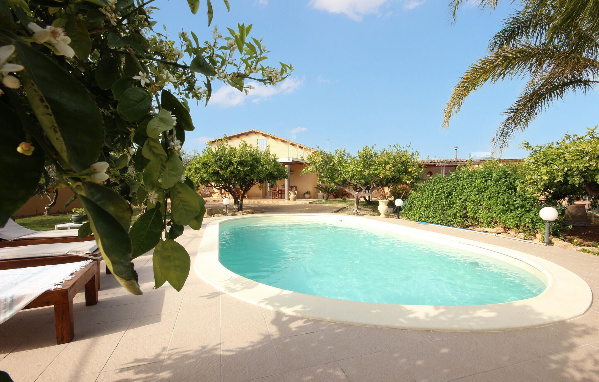 A swimming pool surrounded by a patio area with lounge chairs and a building in the background.