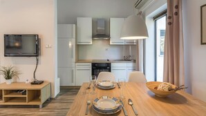 A modern kitchen with white cabinets, a built-in oven, and a dining table set for two with plates, cutlery, and a bowl of food. - Nice apartment in Pula with WiFi (Pula)