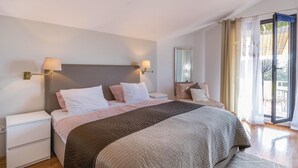 A bedroom with a large bed, two bedside tables, a nightstand, a mirror, and a sliding glass door to a balcony. - Nice apartment in Pula with WiFi (Pula)