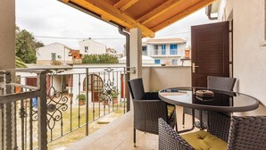 Un balcón con muebles de mimbre, una mesa y vistas a edificios cercanos.