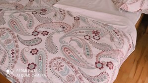 Un lit avec une couvre-lit et des oreillers à motifs floraux, une lampe de chevet et un radiateur.