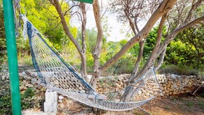 Un hamac suspendu entre des arbres, dans un jardin.