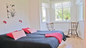 Quarto com duas camas, uma escrivaninha e duas cadeiras.