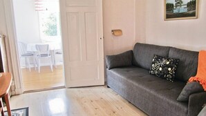Sala de estar com um sofá cinzento, uma mesa pequena e cadeiras.