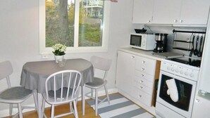 Uma cozinha compacta com mesa de jantar, cadeiras, micro-ondas, cafeteira e forno.