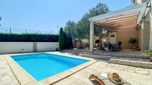 Une piscine avec des chaises longues et un espace patio couvert.
