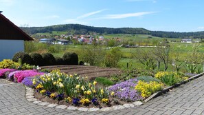A landscaped garden with flower beds and a view of a village in the distance.
