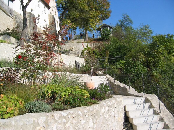 A stone staircase leading up to a building with a white facade, surrounded by greenery and trees.