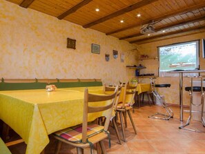 Un restaurante con mesas y sillas de madera, una pantalla de proyector y un piso de baldosas.