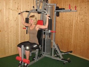 A person using a gym machine with a wooden wall background.