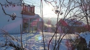Una casa con puerta de cristal, balcón y un patio nevado.