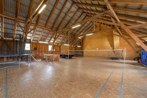 Un gimnasio interior con suelo de madera, pared de escalada y diverso equipamiento deportivo.