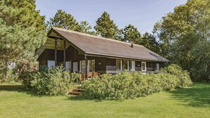 Eine Holzhütte mit Veranda, umgeben von dichtem Grün und Bäumen.