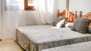 A bedroom with a bed, a window with curtains, and a wooden headboard.