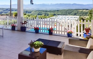 Une terrasse avec des sièges extérieurs, des plantes en pot et une vue sur un paysage montagneux.