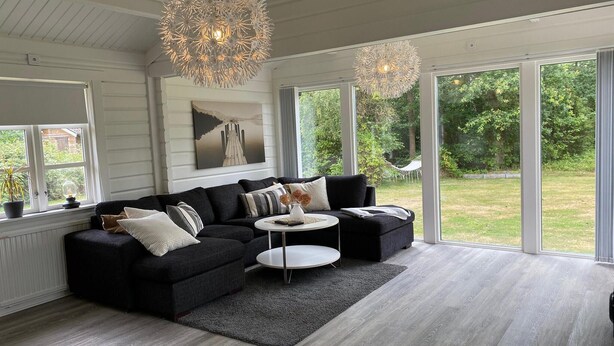 A modern living room with a sectional sofa, a round coffee table, and a large window offering a view of the outdoors.