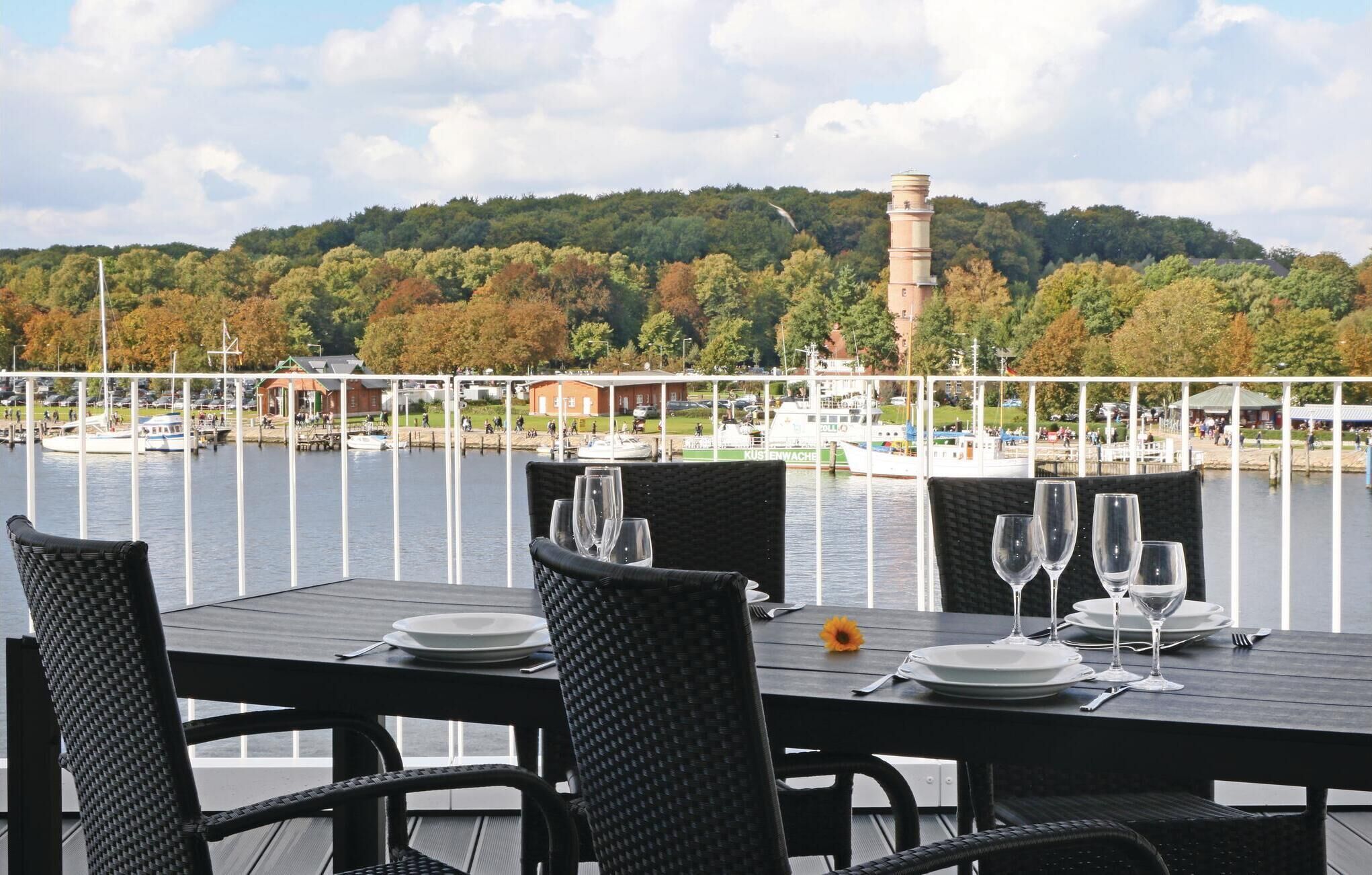 A table set for dining with a view of a marina and a hill in the background.