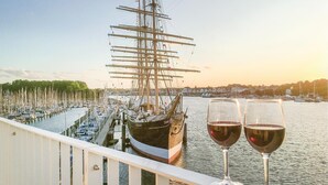 Un navire était amarré dans une marina, et deux verres de vin rouge étaient posés sur une rambarde.