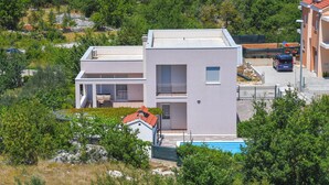 A modern two-story house with a balcony, a swimming pool, and a car parked in the driveway. - Cozy home in Dugopolje (Dugopolje)