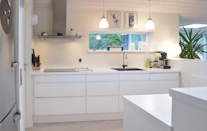 A modern kitchen with white cabinetry, a built-in stove, and a window with a view of greenery. - Nice home in Ringkøbing with kitchen (Ringkøbing)