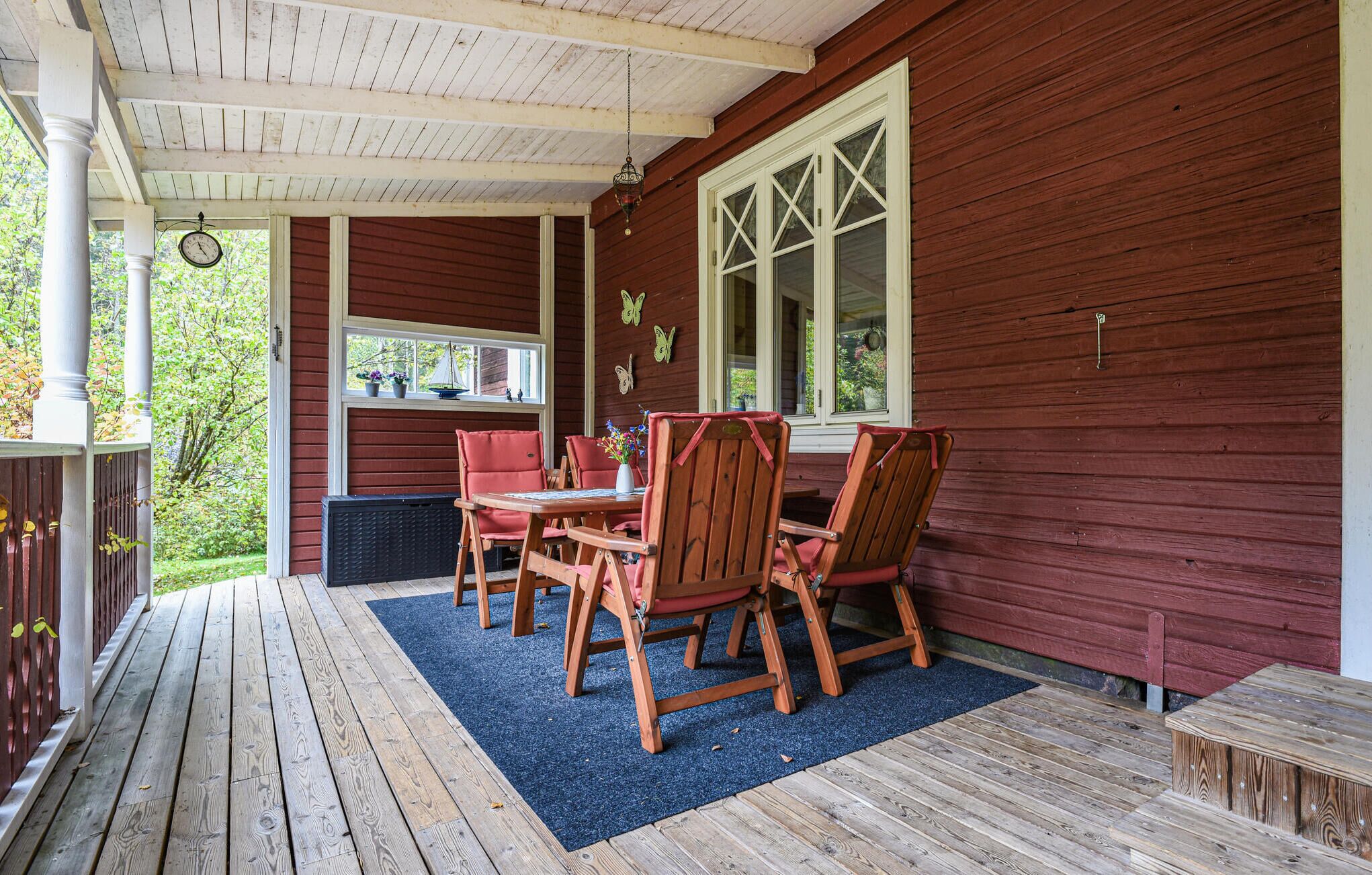 A covered porch with wooden furniture and a window with shutters.