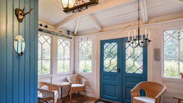 A cozy room with wicker furniture, a blue door, and a decorative mirror.