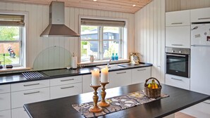 A modern kitchen with white cabinetry, a central island with candles, and a view of the outside. - Cozy home in Frederikshavn with kitchen (Frederikshavn)