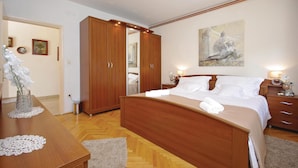 Une chambre à coucher avec un lit en bois, une table de chevet, une armoire et un tableau accroché au mur.