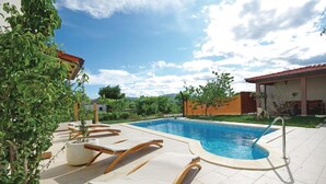 Une piscine dotée de chaises longues, d’une pergola et offrant une vue sur le paysage environnant.