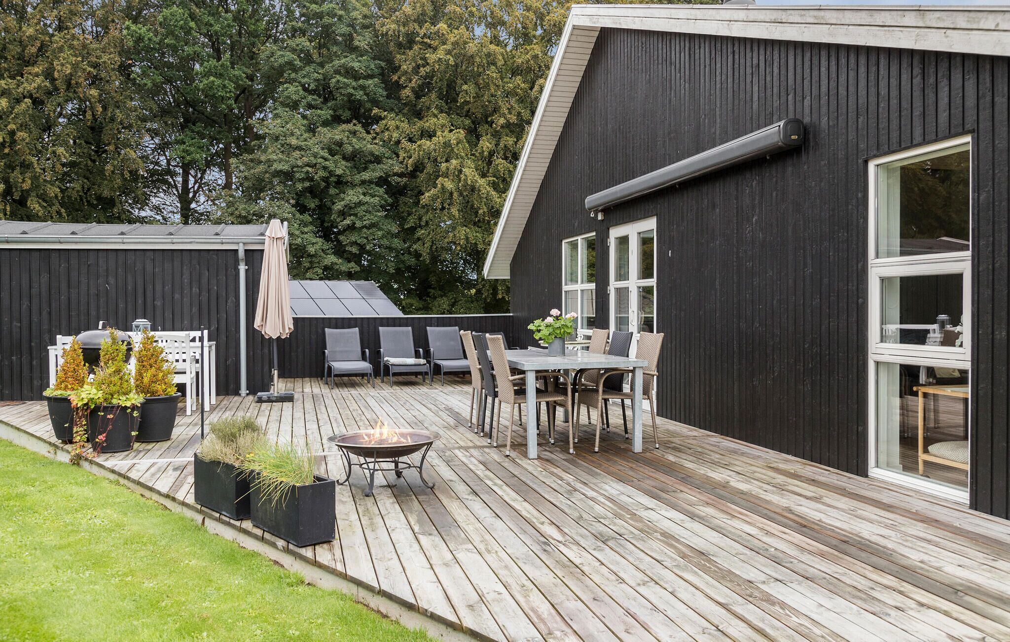 Une terrasse dotée de mobilier d’extérieur, d’un foyer et de plantes en pot.