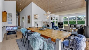 Un salón amplio con una mesa de comedor de madera, asientos cómodos y un gran ventanal con vistas al exterior.