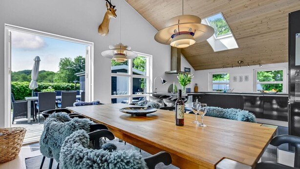 Una cocina moderna con una mesa de madera, sillas y una cabeza de animal colgada.