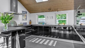 Una cocina moderna con armarios negros, techo de madera y alfombra a cuadros.