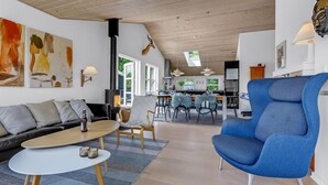 Una sala moderna con un sofá, un sillón azul y una zona de comedor con una mesa y sillas.