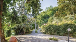Un chemin pavé traverse un jardin luxuriant où l’on trouve une grande variété d’arbres et d’arbustes.