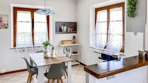 Un espace repas comprenant une table en bois, des chaises, un luminaire suspendu et un comptoir de cuisine.